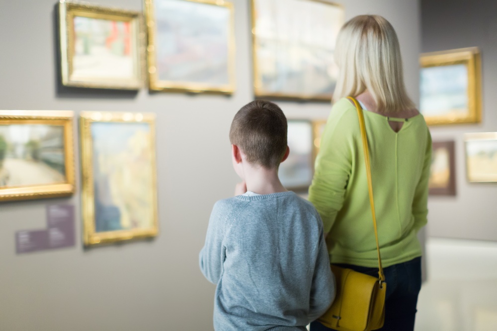 Ordinary mother and son exploring paintings in halls of museum